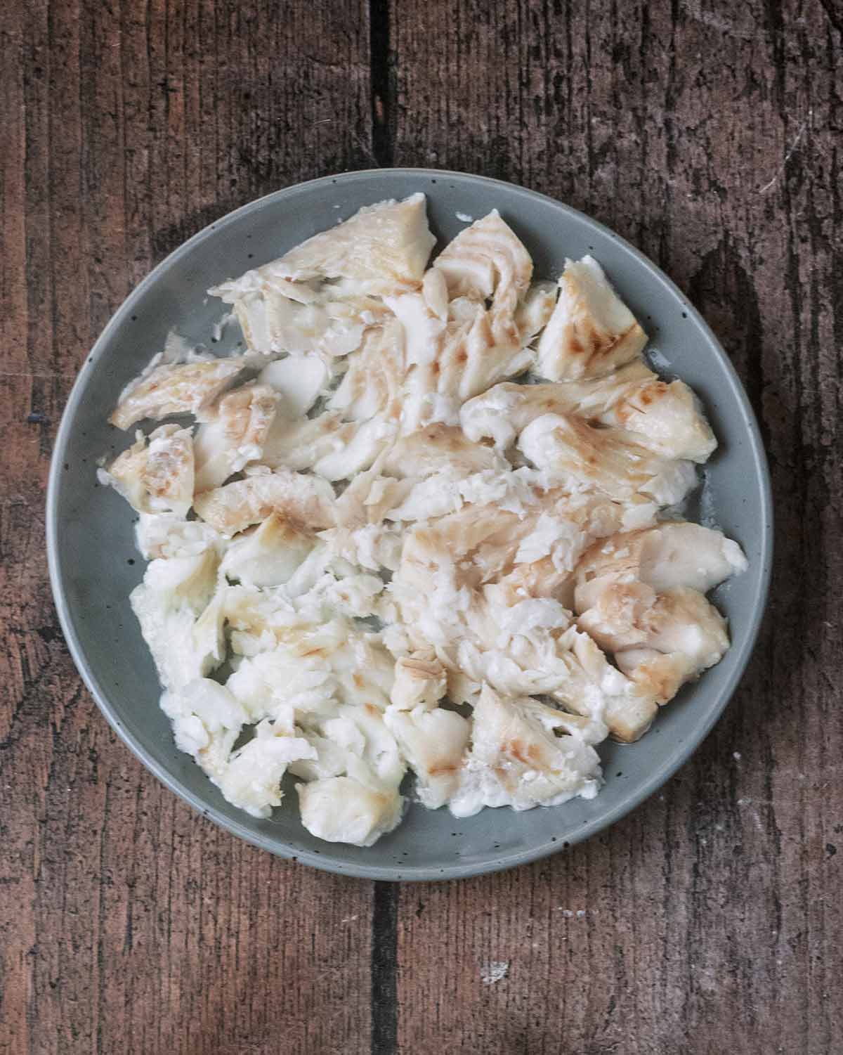 Cooked, flaked white fish on a plate.
