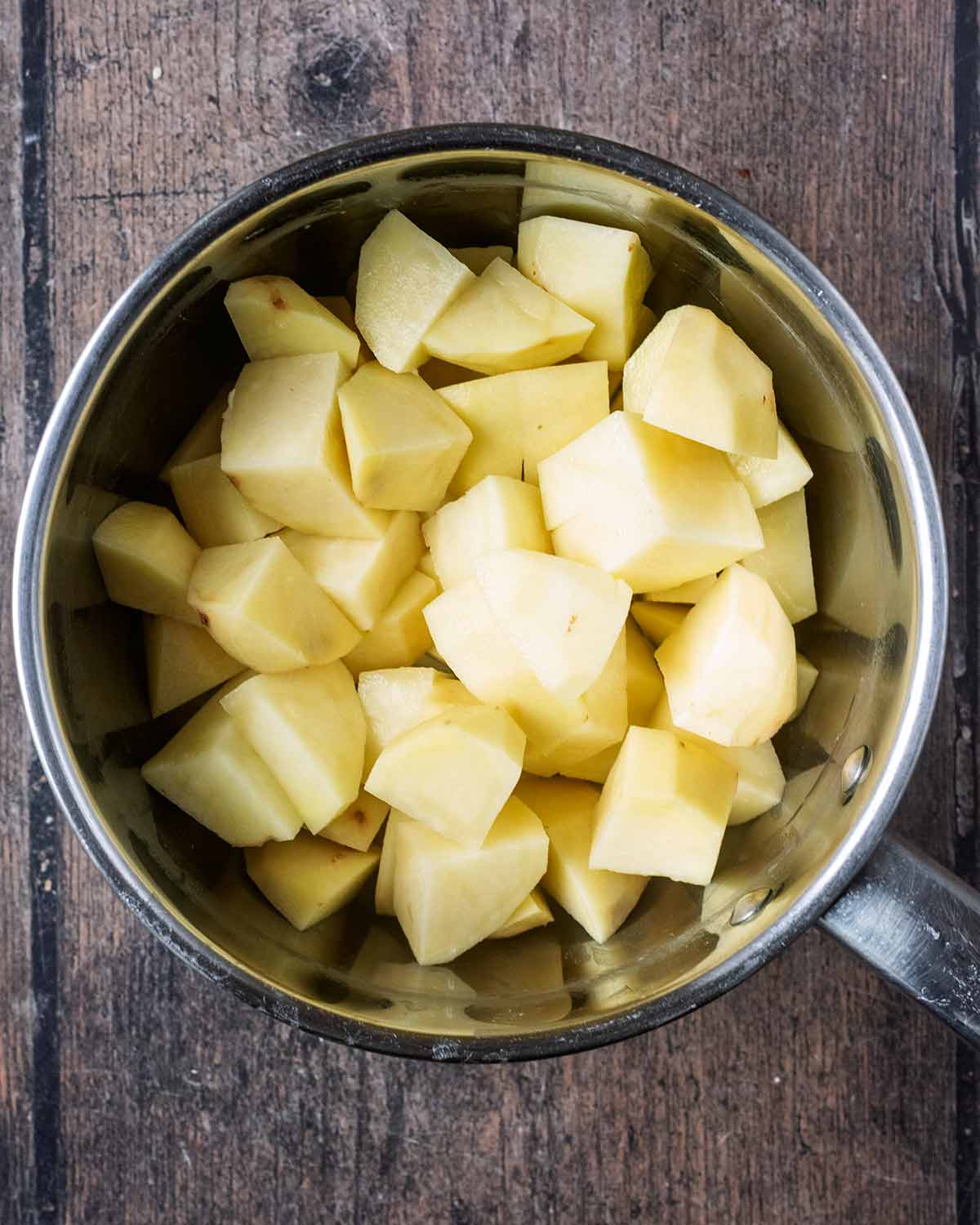 A saucepan with chopped potatoes in it.
