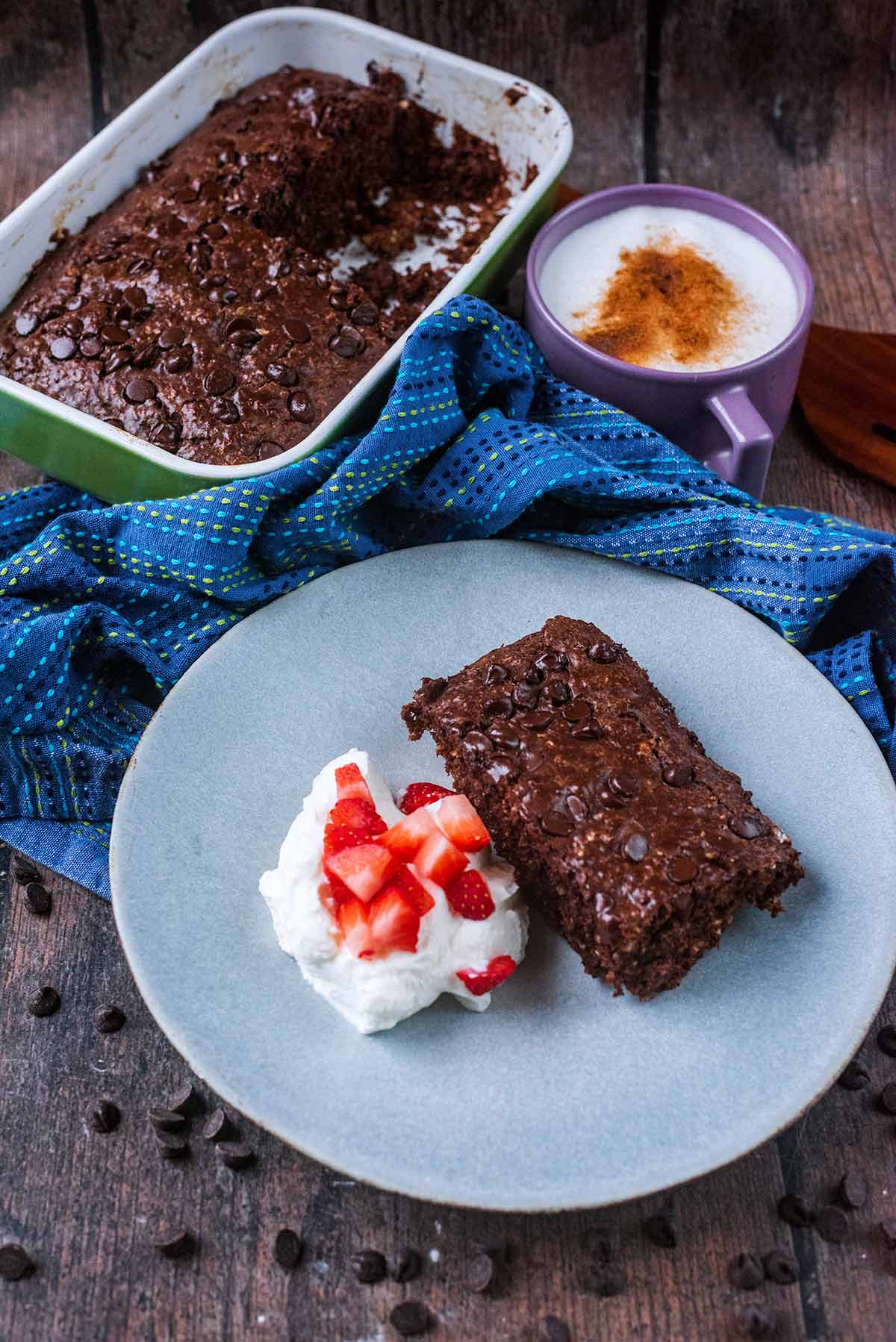 A plate of chocolate baked oats in front of a towl and a dish of more baked oats.