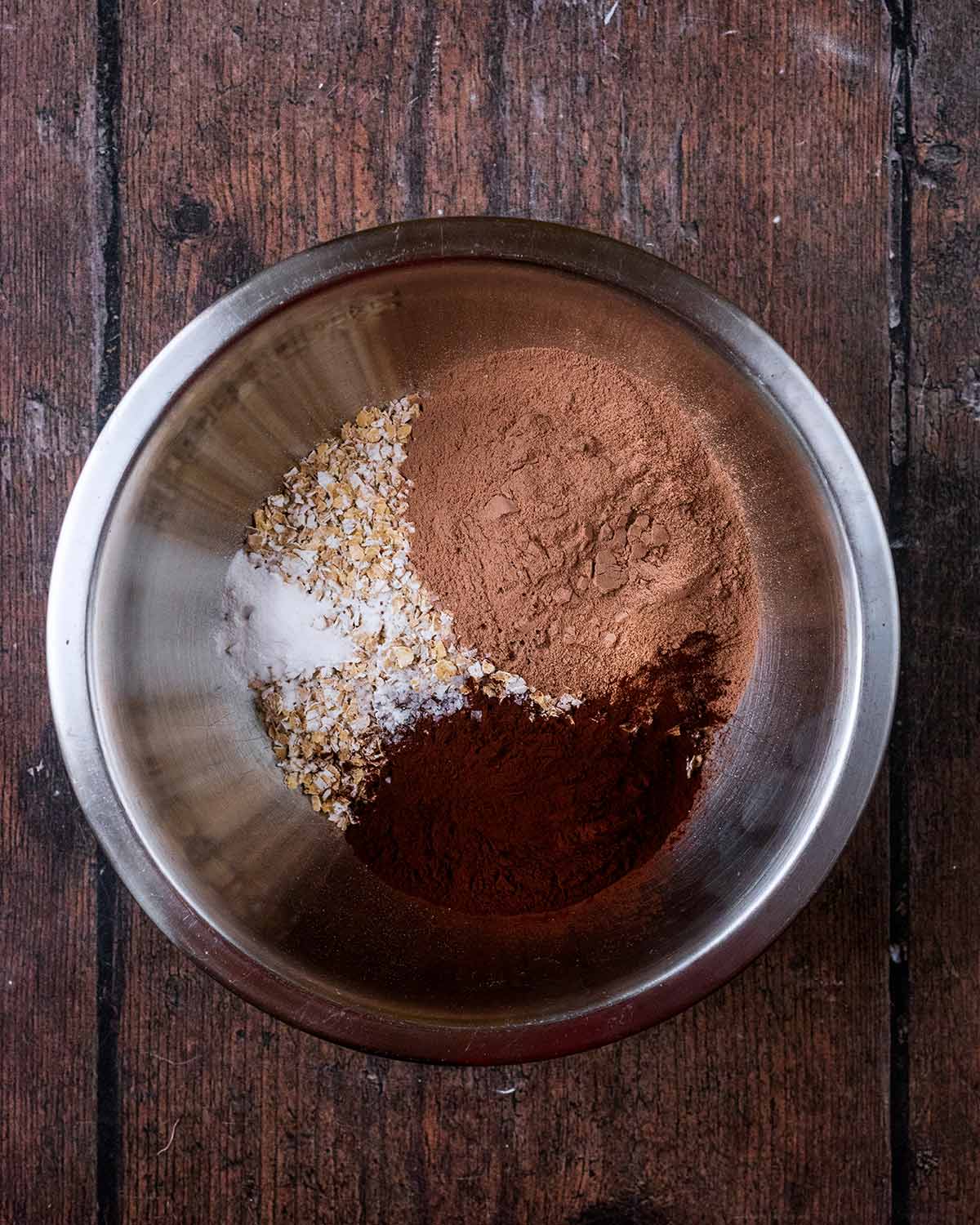 Oats, protein powder and cocoa powder in a mixing bowl.
