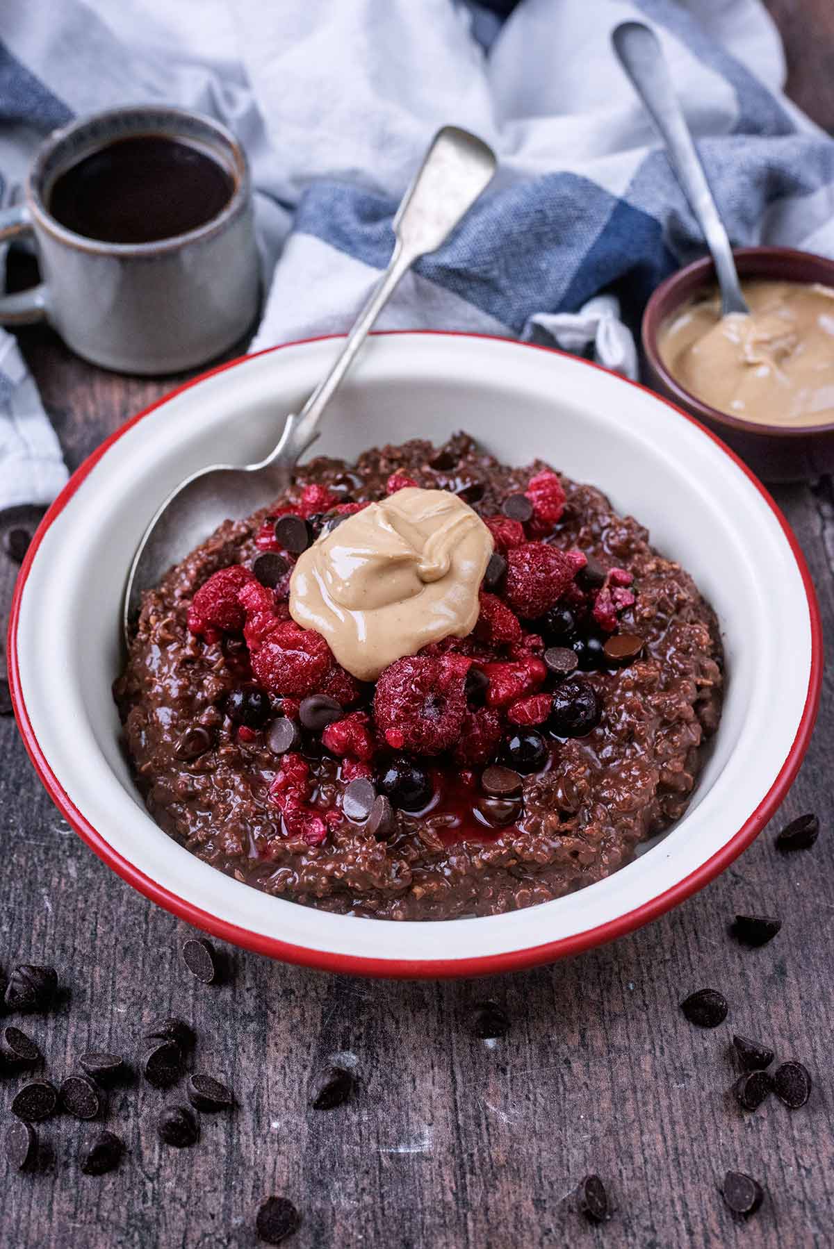 A bowl of chocolate porridge in front of a towel and a small cup of coffee.