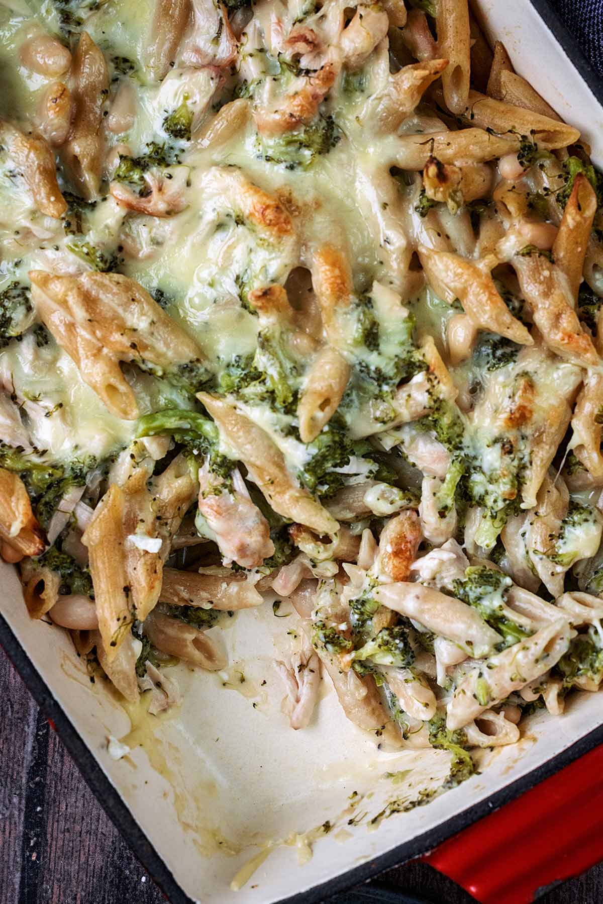 A tray of pasta bake with a portion removed.