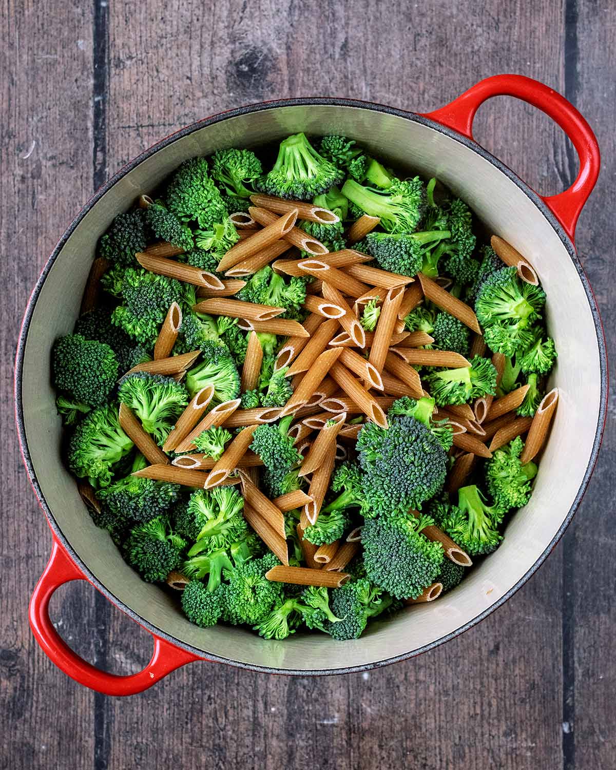 A large pan of penne pasta and broccoli florets.
