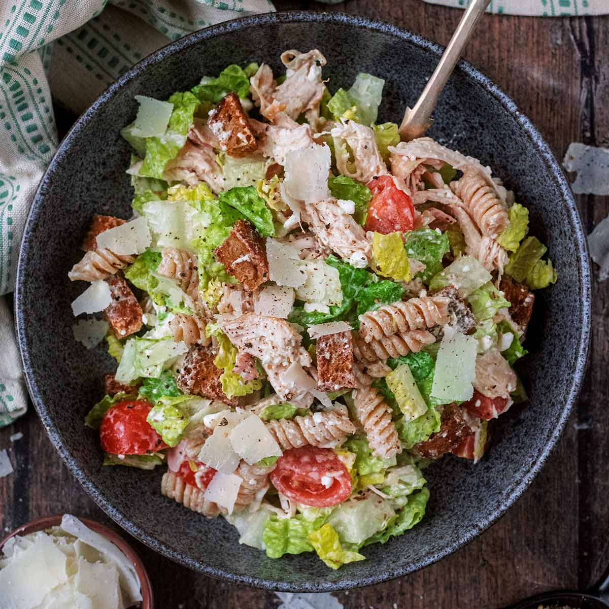 Chicken Caesar pasta salad in a round blue bowl with a fork in it.