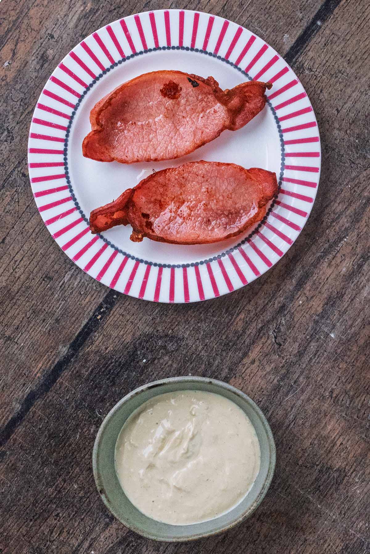 A plate of cooked bacon and a bowl of salad dressing.