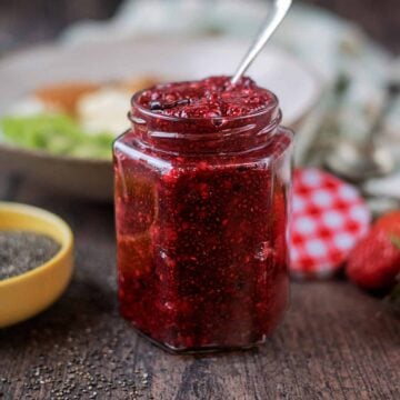 A jar of chia seed jam with a small spoon in it.
