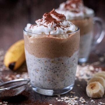 Banoffee overnight oats in a glass mug with another mug behind it.