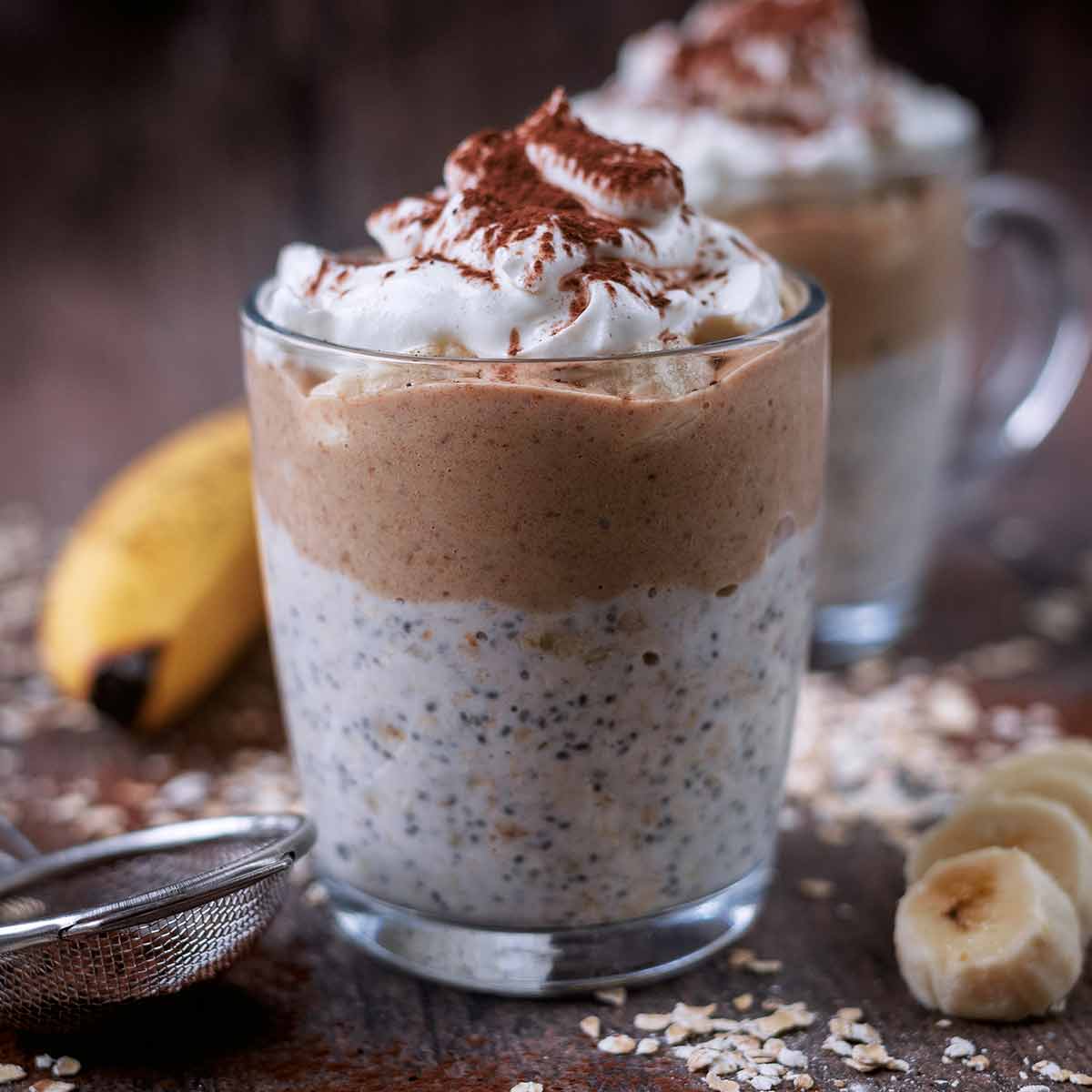 Banoffee overnight oats in a glass mug with another mug behind it.