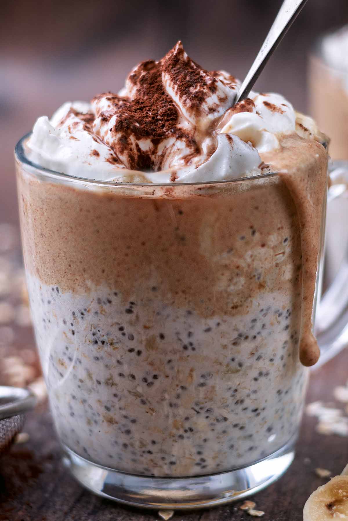 A glass of overnight oats with caramel dripping down the outside of the glass.