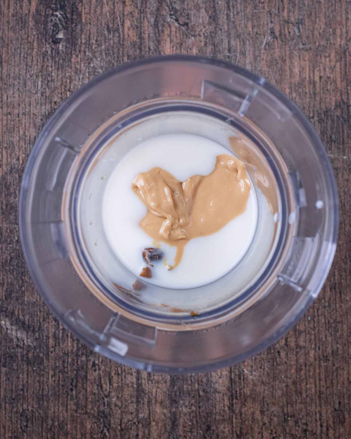 Milk, cashew butter and dates in a small blender jug.