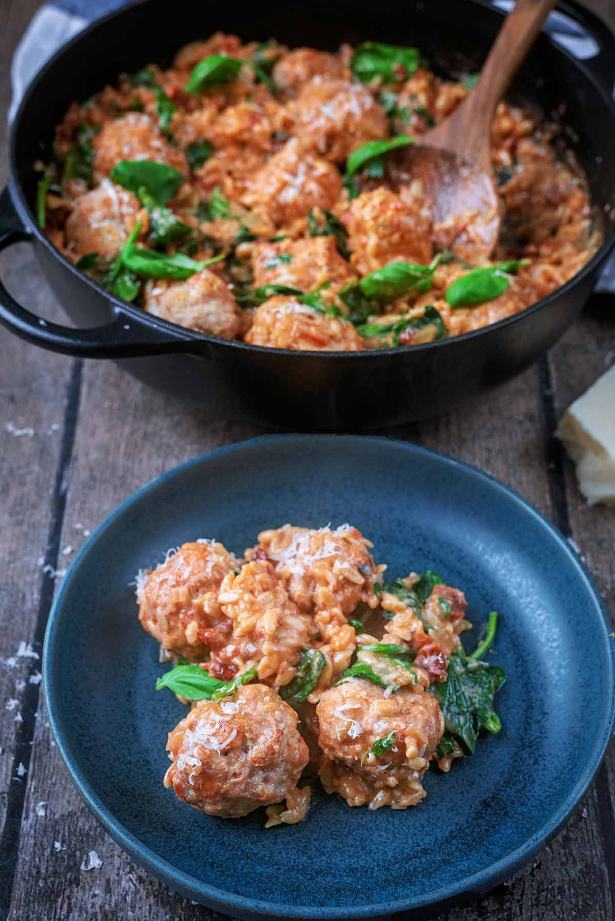A bowl of meatballs in a creamy sauce in front of a pan of more meatballs in sauce.