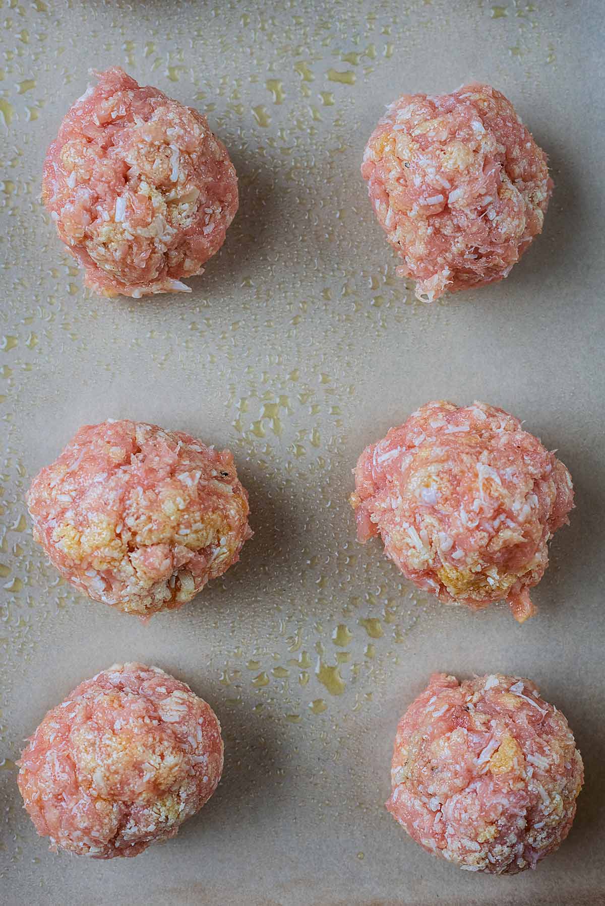 Six meatballs on a lined baking sheet.