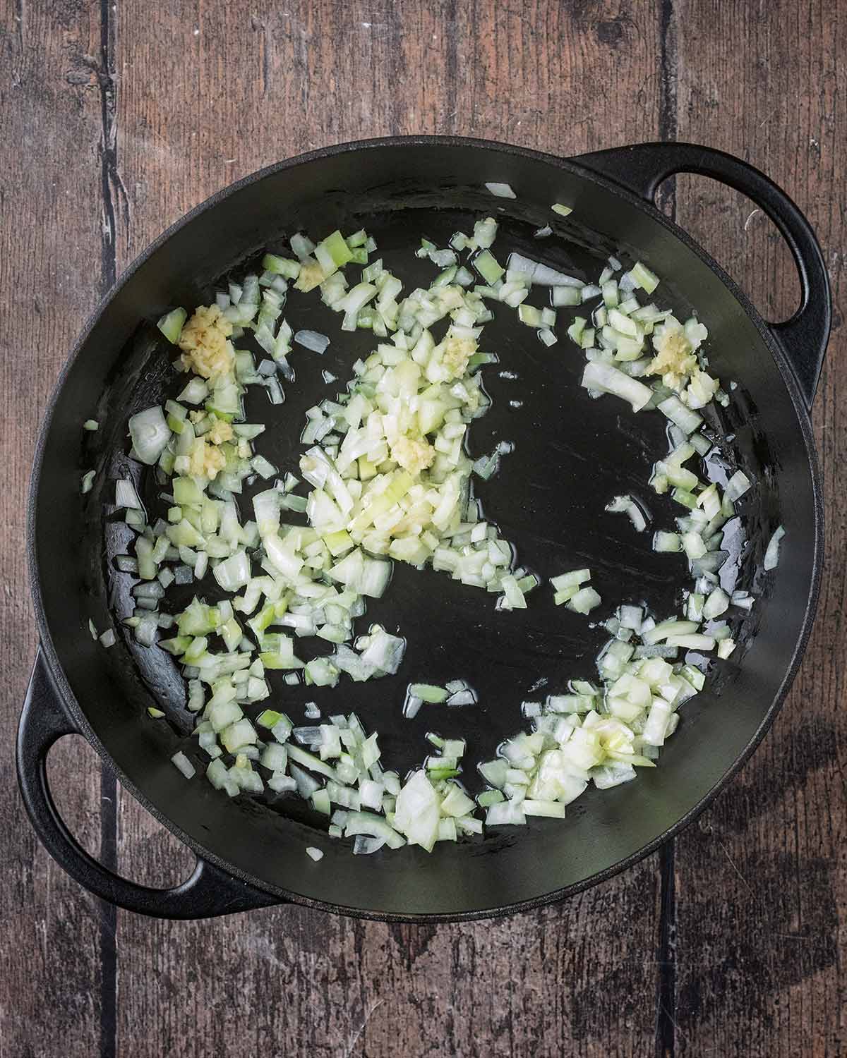 Chopped onions cooking in a large black pan.