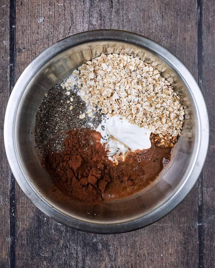 A mixing bowl containing oats, cocoa, yogurt, and chia seeds.
