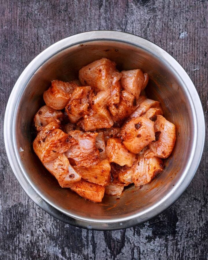 Chicken chunks in a mixing bowl coated with chipotle paste.