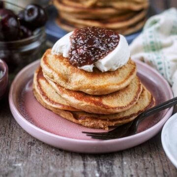 A stack of blender protein pancakes topped with yogurt and jam.