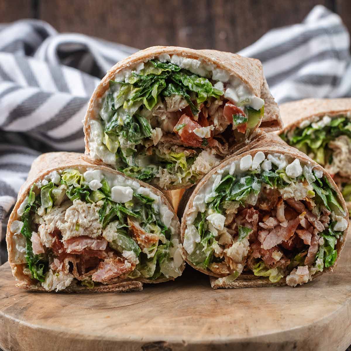 Three high protein chicken caesar wraps stacked in a triangle.