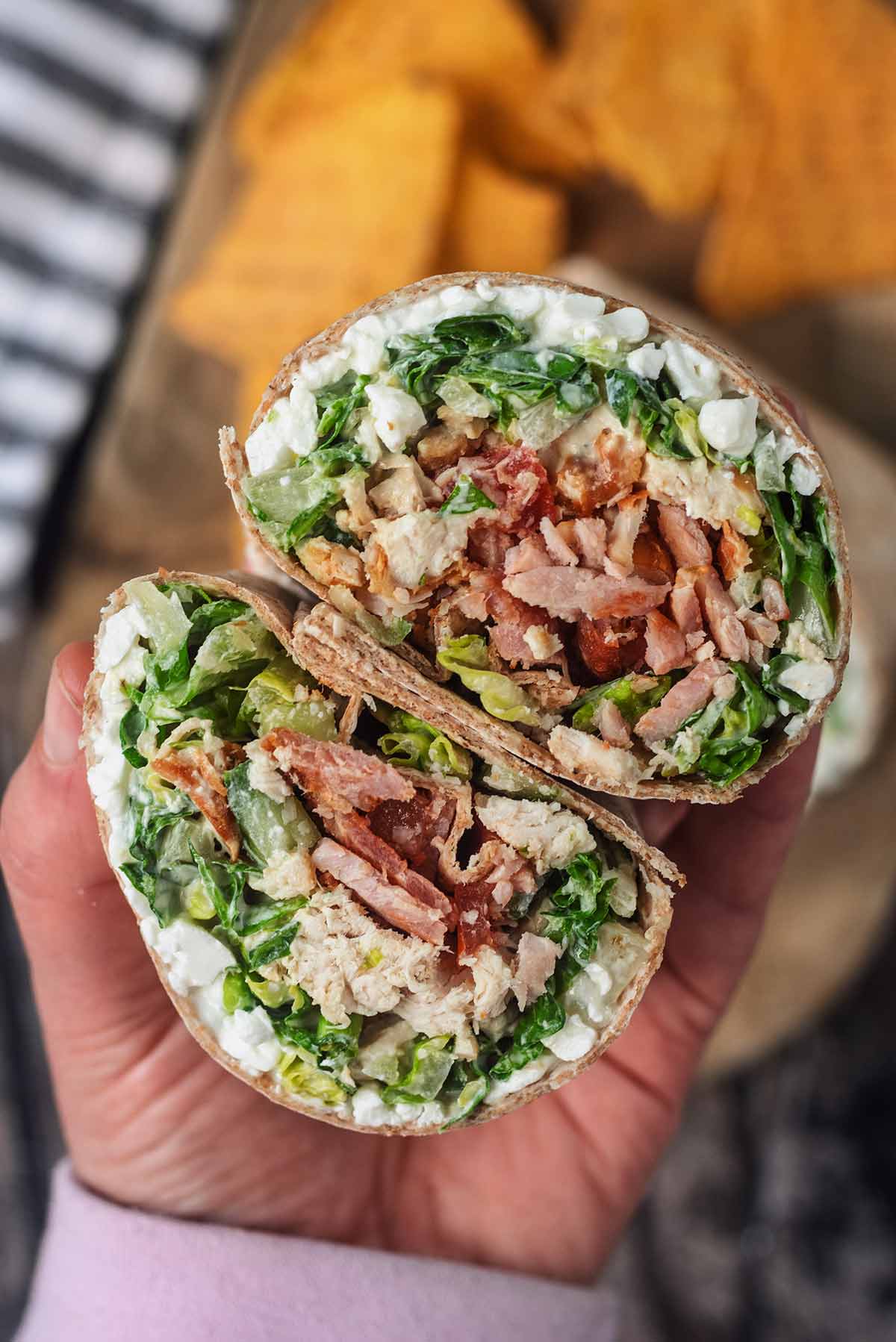 A hand holding two halves of a chicken salad wrap.