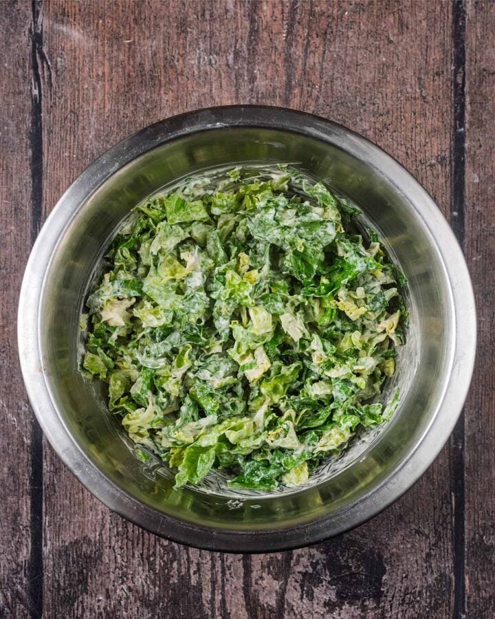A bowl of chopped lettuce mixed with a creamy salad dressing.