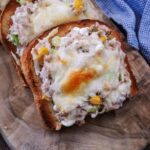 A slice of high protein tuna melt on a wooden board.