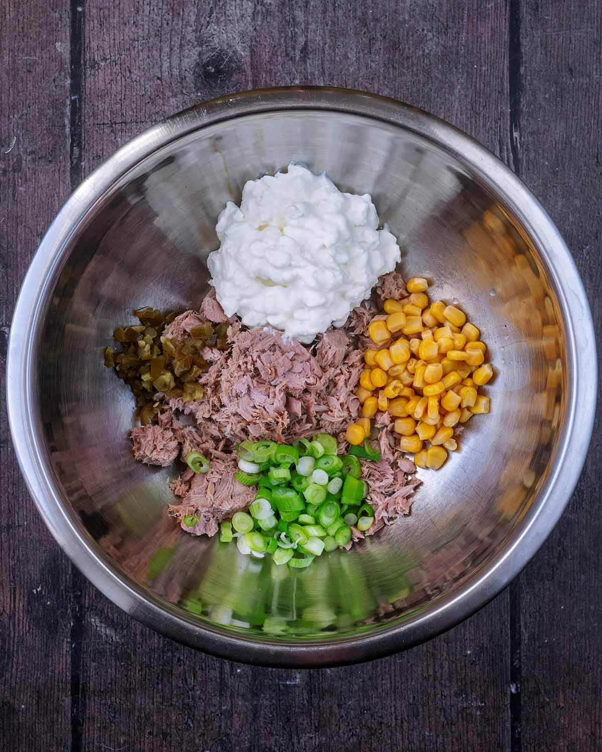 A large mixing bowl containing tuna, sweetcorn, sliced spring onions, chopped jalapo&ntilde;os and cottage cheese.