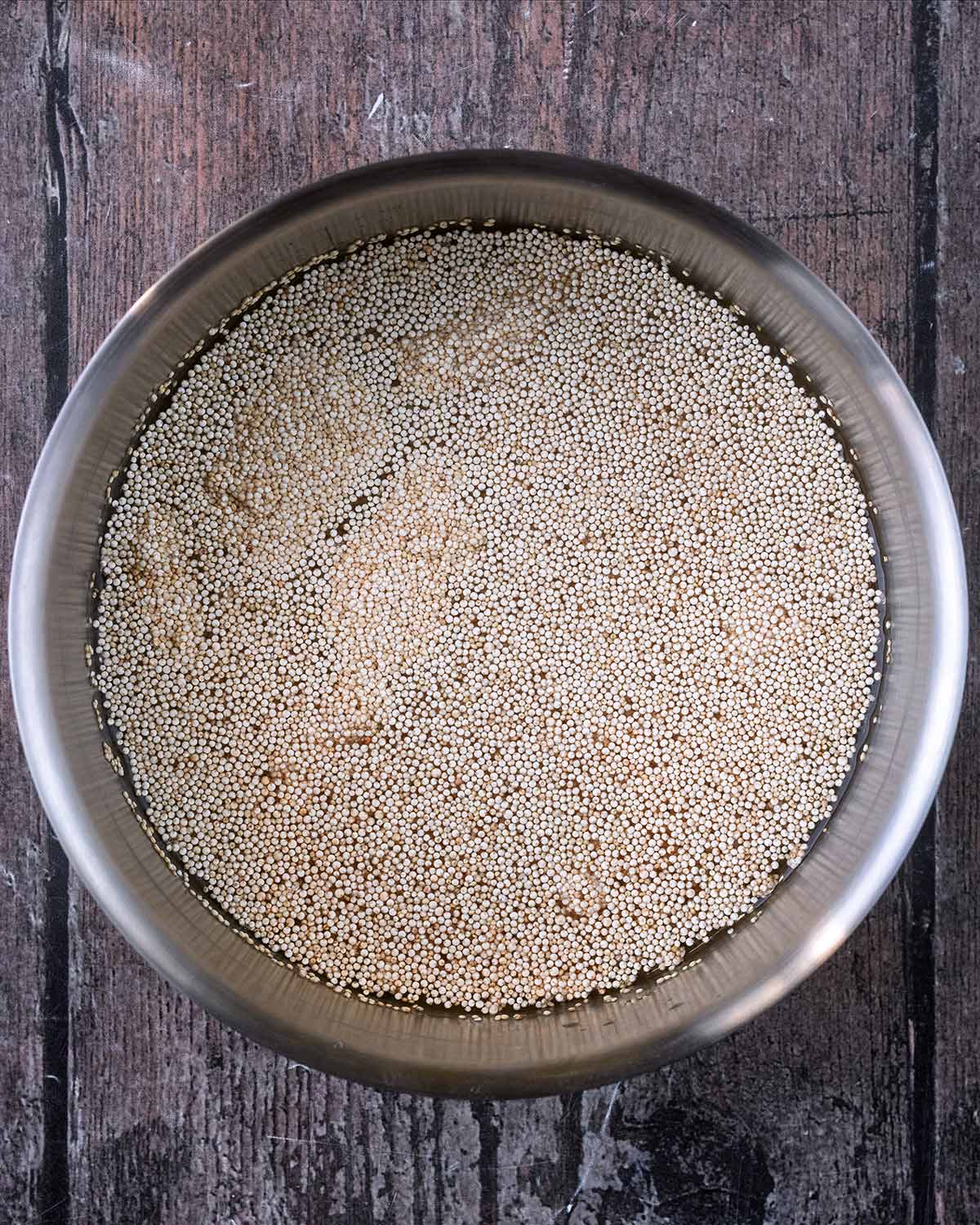 A saucepan containing uncooked quinoa and water.