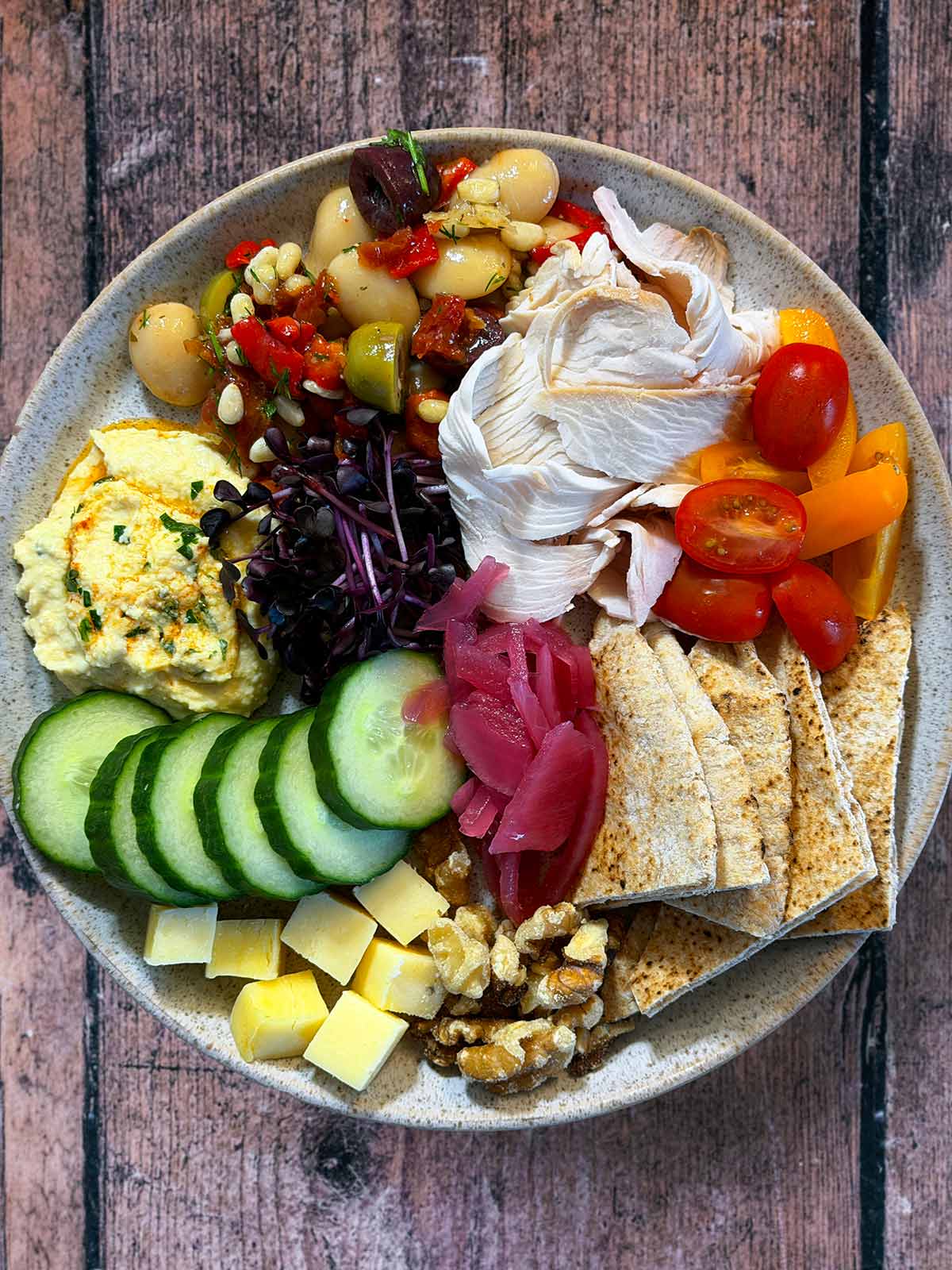 A picky plate made up of salad items, flatbread, beans, hummus and turkey slices.