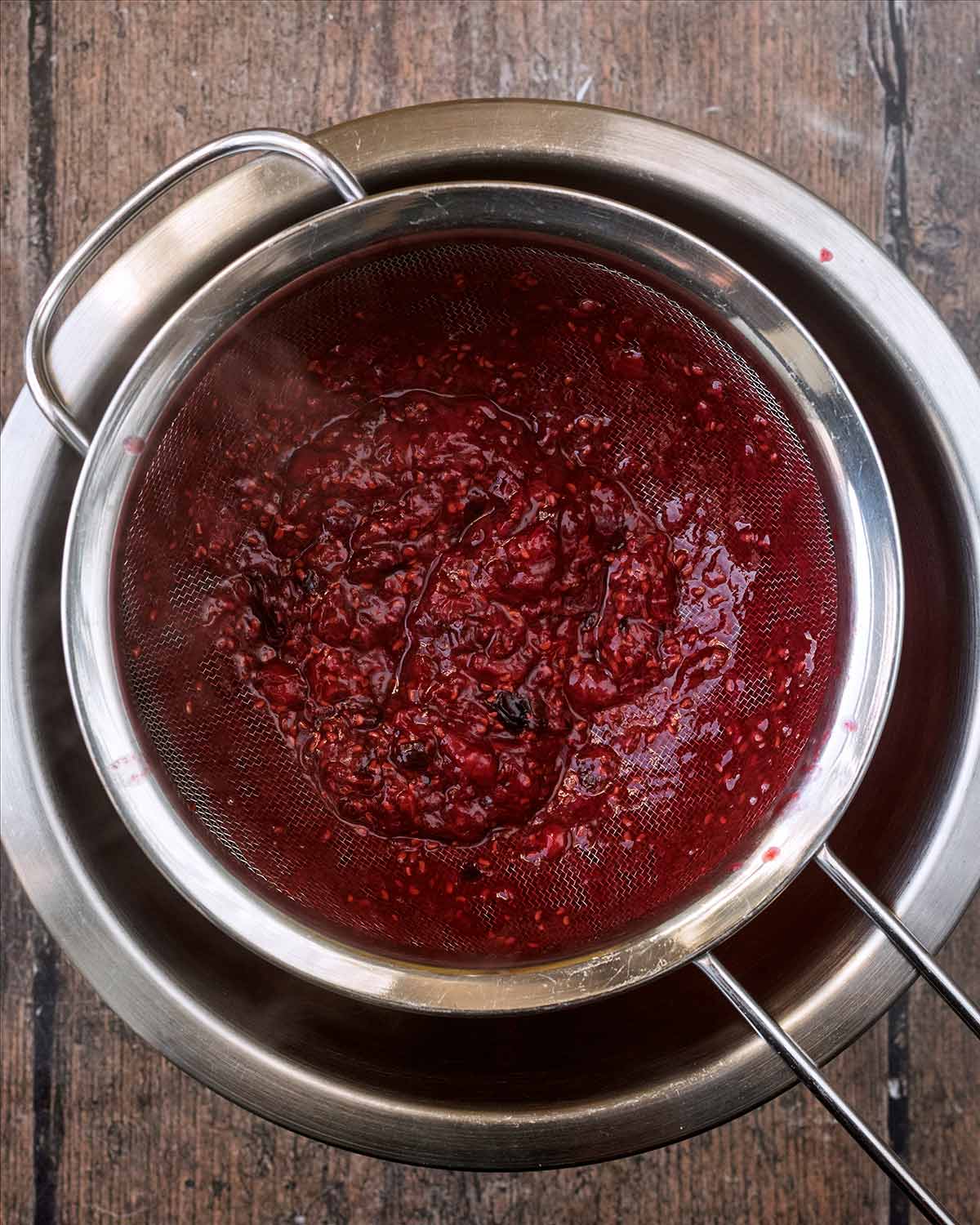 A sieve over a bowl with strained berries in it.