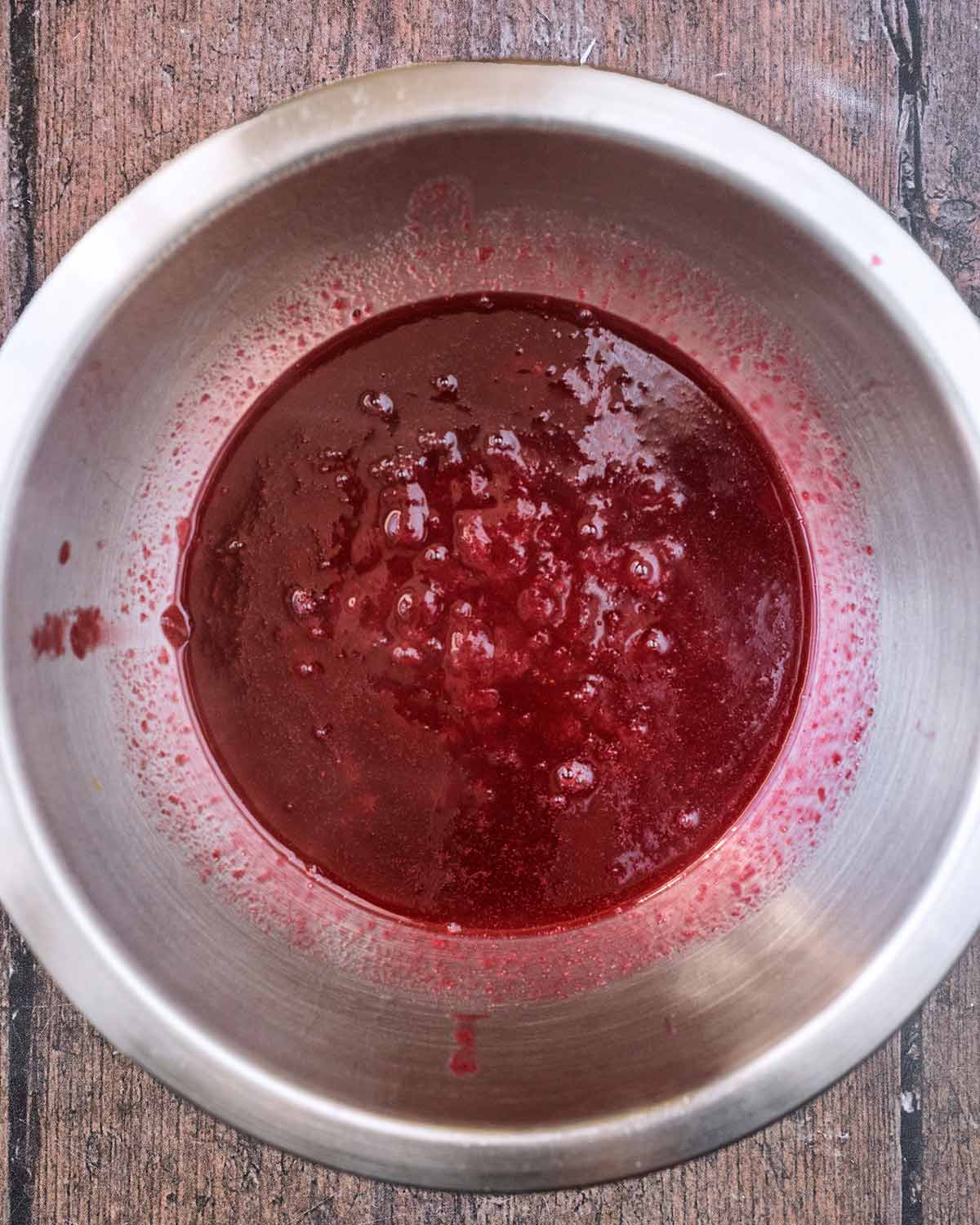 A stainless steel bowl containing strained berry juice.