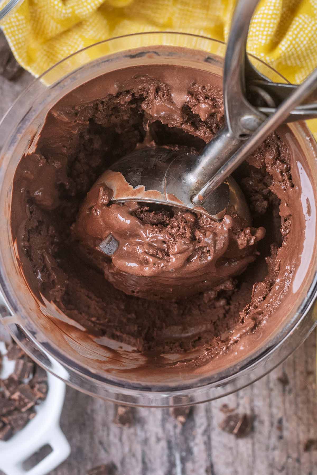 Chocolate ice cream being scooped out of a ninja Creami pint tub.