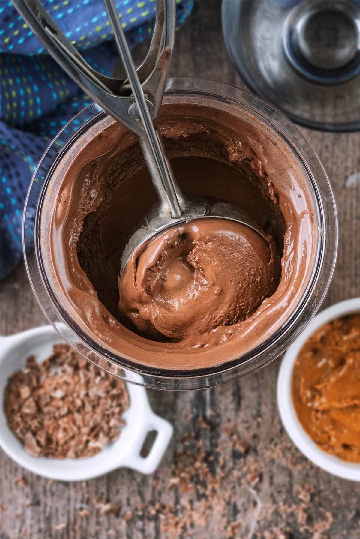An ice cream scoop scooping some chocolate ice cream out of a Ninja Creami tub.