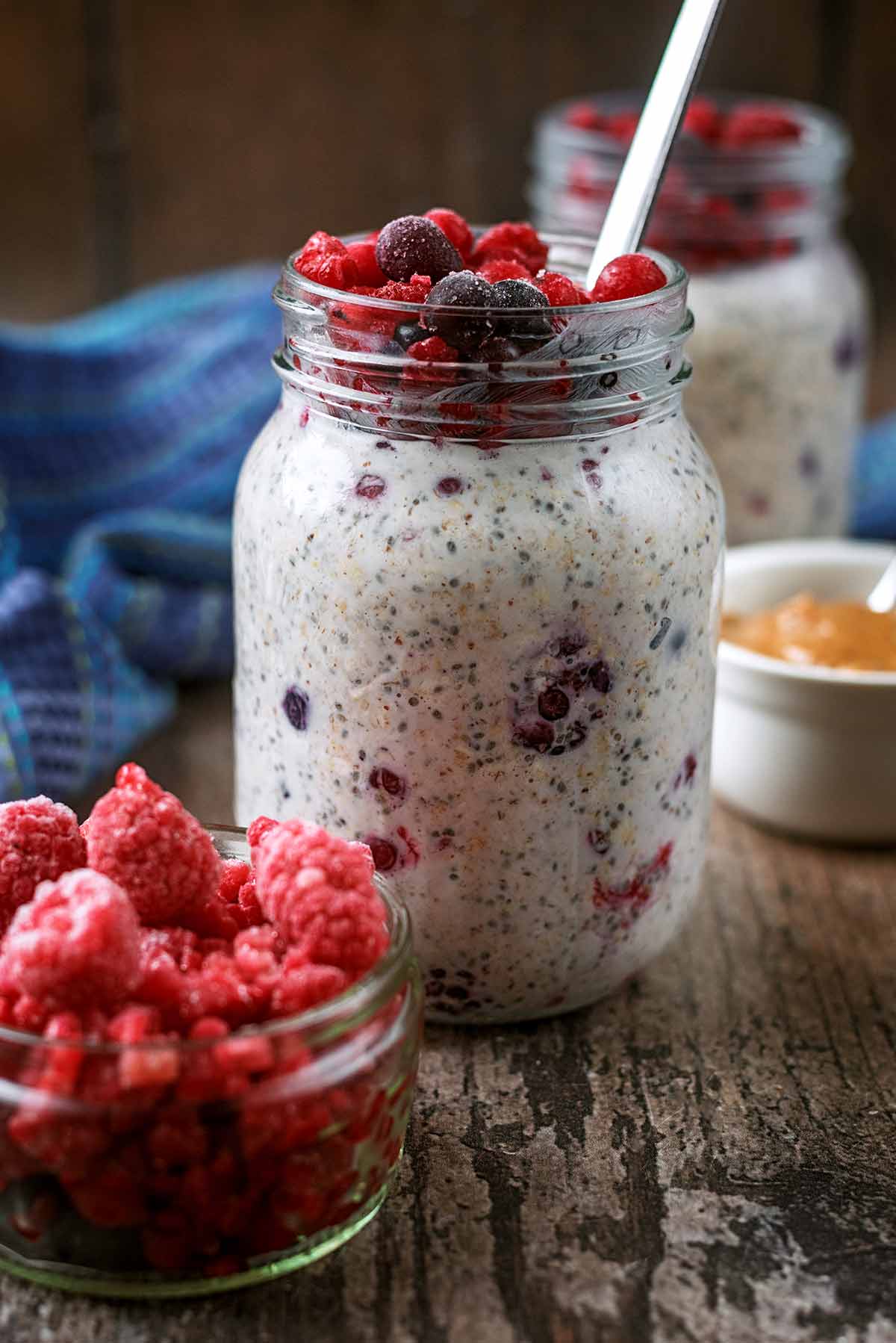 A jar of overnight oats topped with some berries, with a small bowl of berries in front.