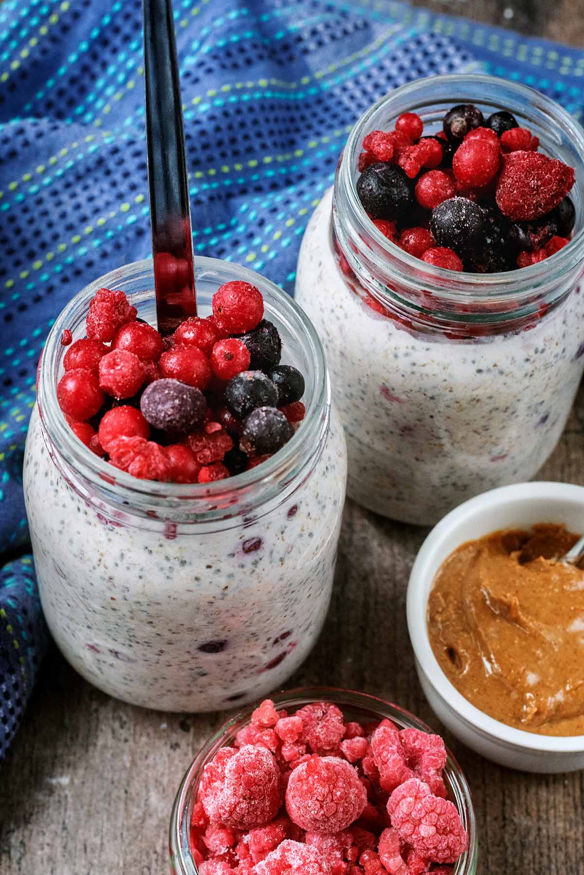 Frozen berries on top of two jars of overnight oats.