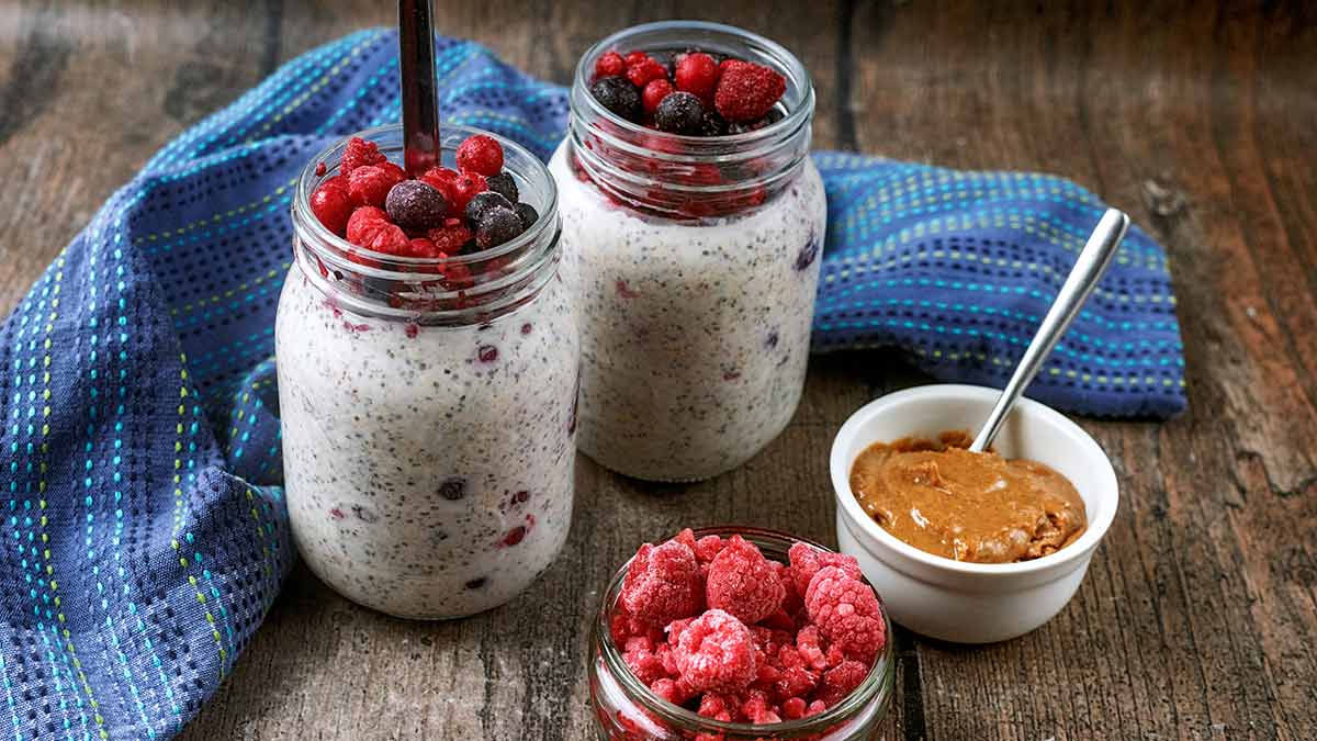 Two jars of overnight oats with frozen berries.