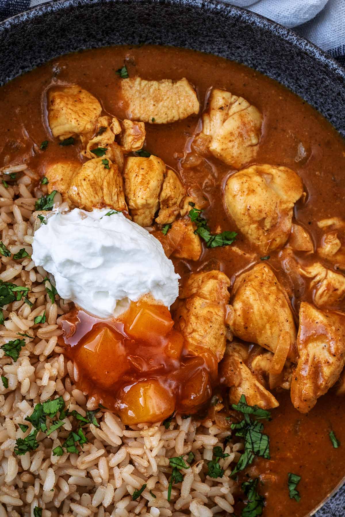 Chicken curry and rice topped with a dollop of yogurt and some mango chutney.