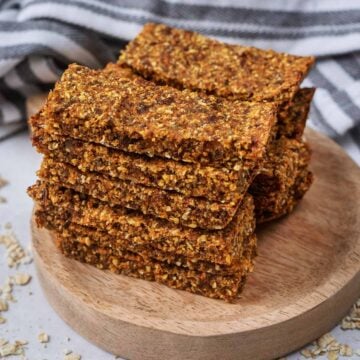 A stack of carrot cake oat bars on a small wooden serving board.