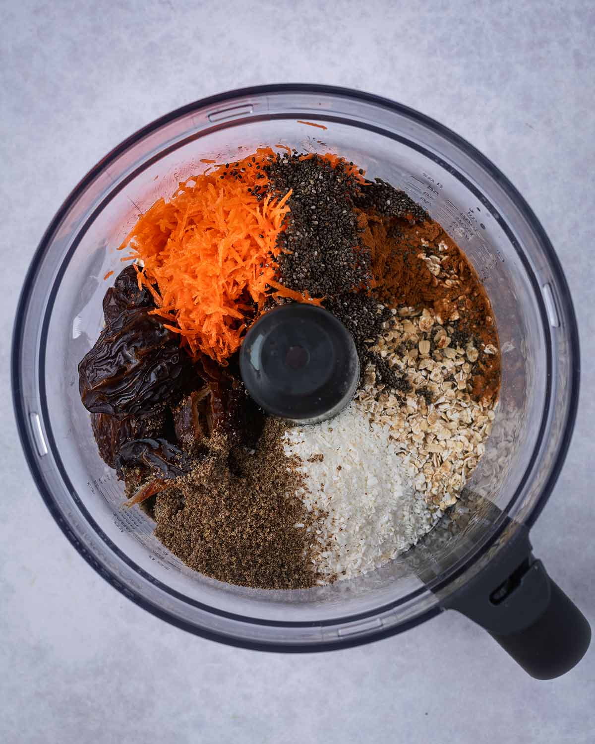 Grated carrot, dates, seeds, coconut, oats and cinnamon in a food processor.