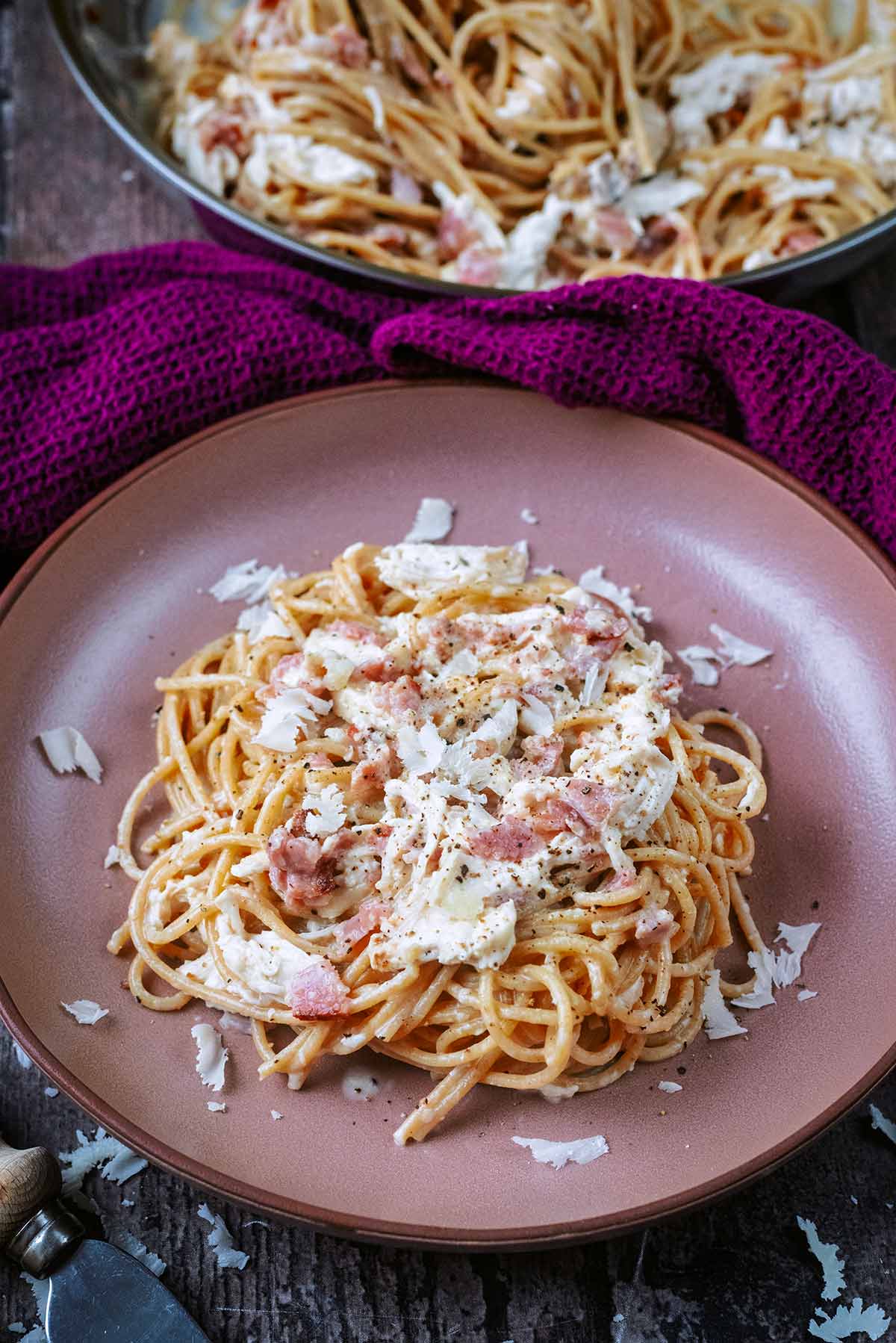 A bowl of carbonara in front of a pan of more carbonara.