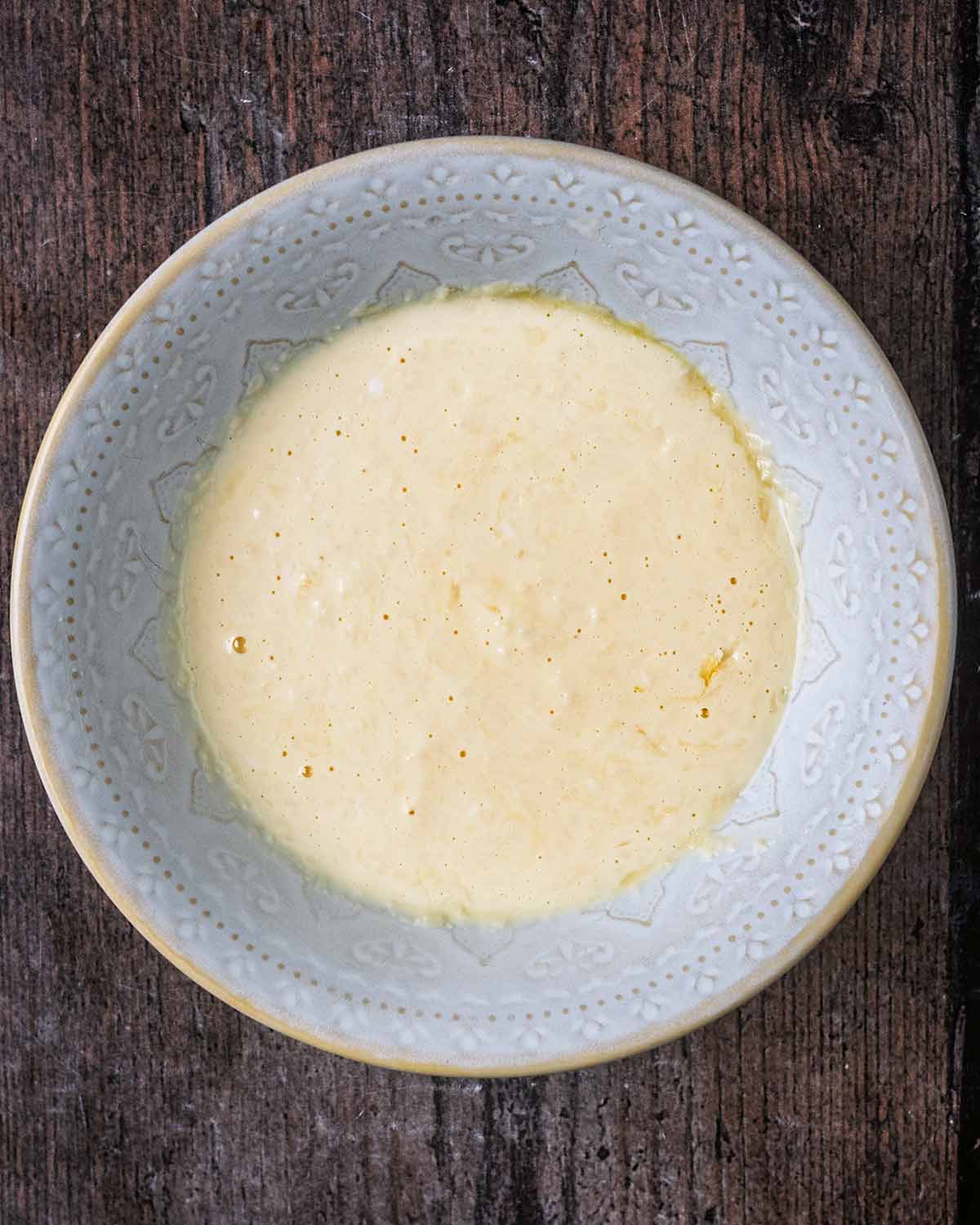 A bowl with a mixture of whisked egg, yogurt and grated cheese.