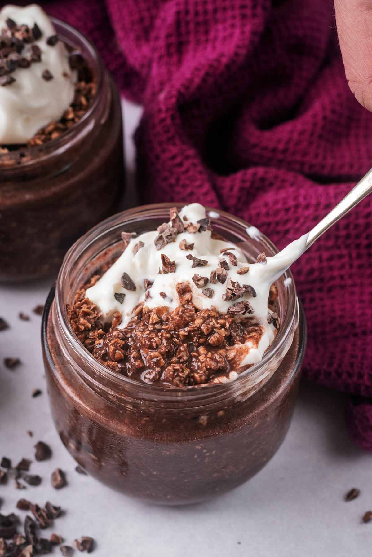 A spoon lifting some overnight oats out of a jar.