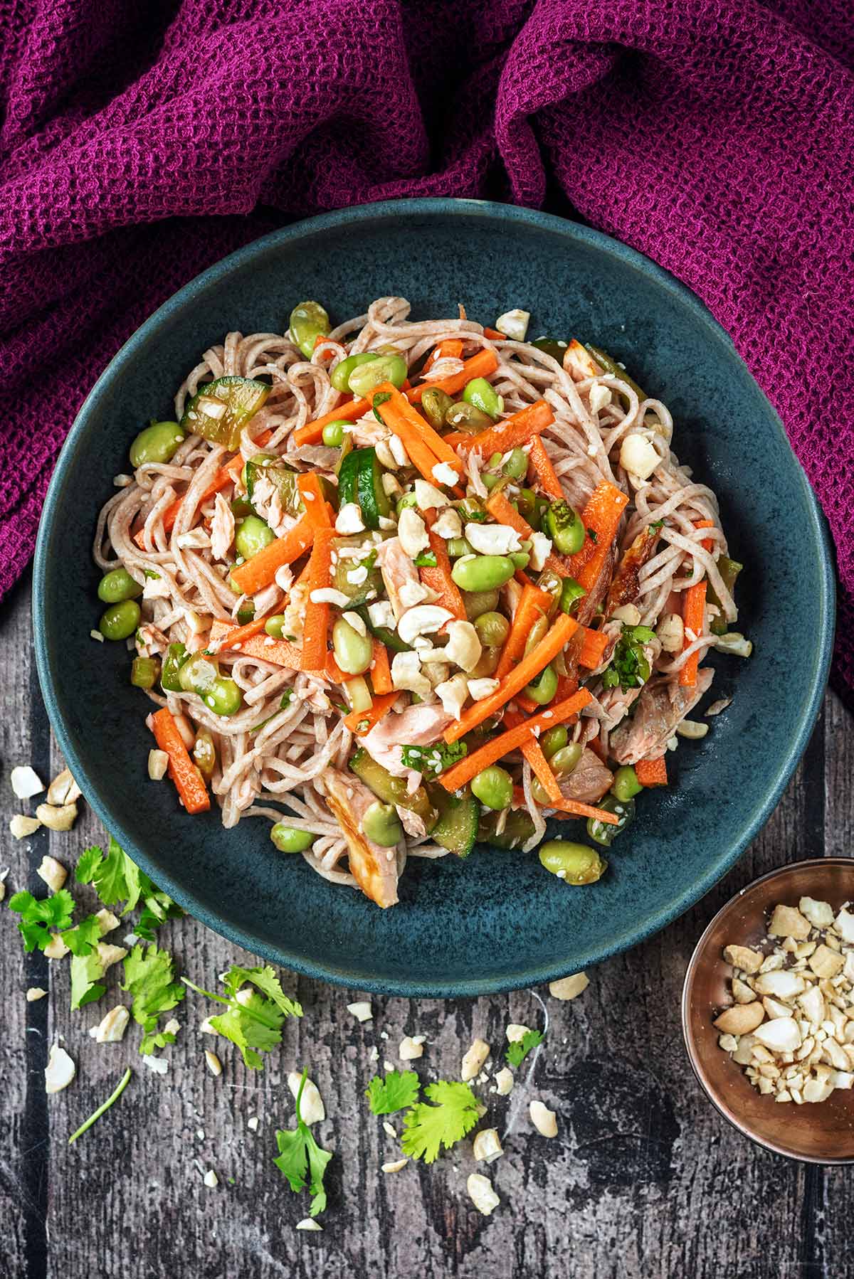 A bowl of noodles mixed with vegetables and flaked salmon.