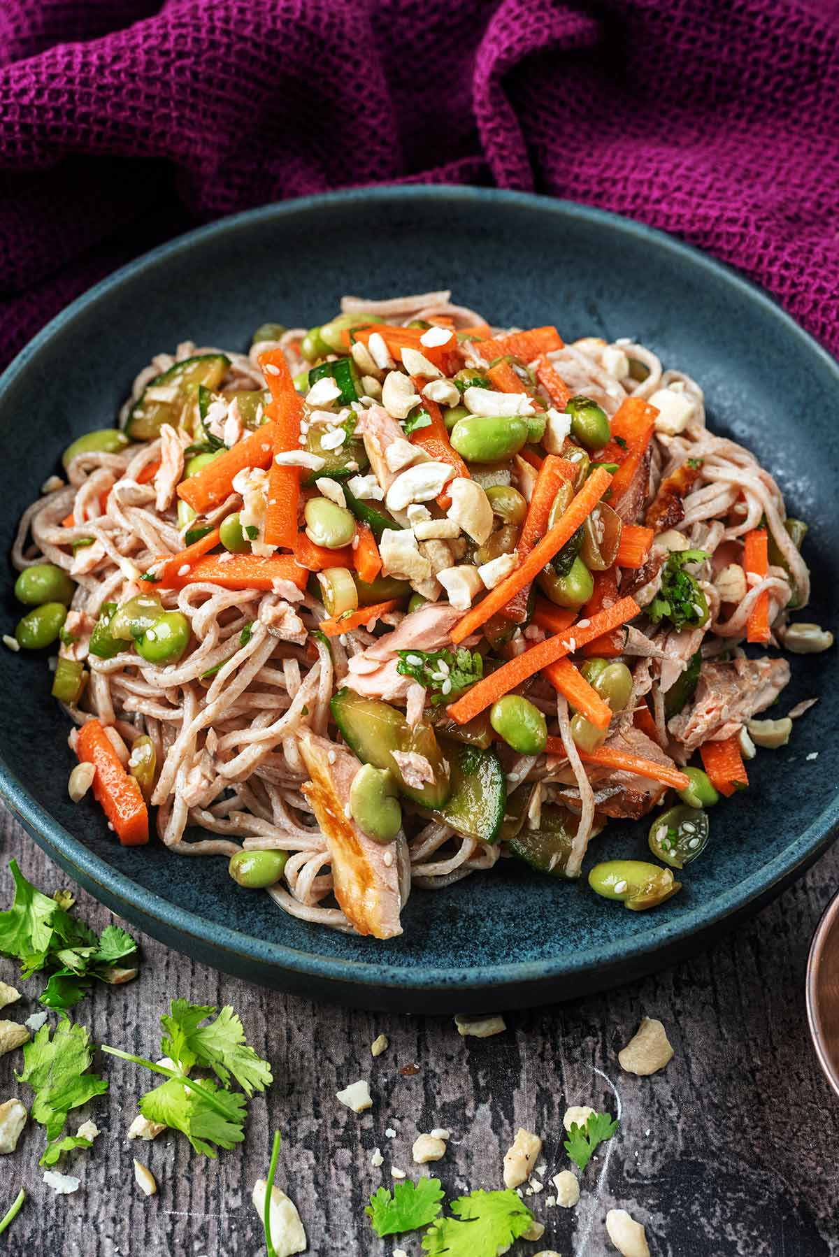 A bowl of noodle salad in front of a purple towel.