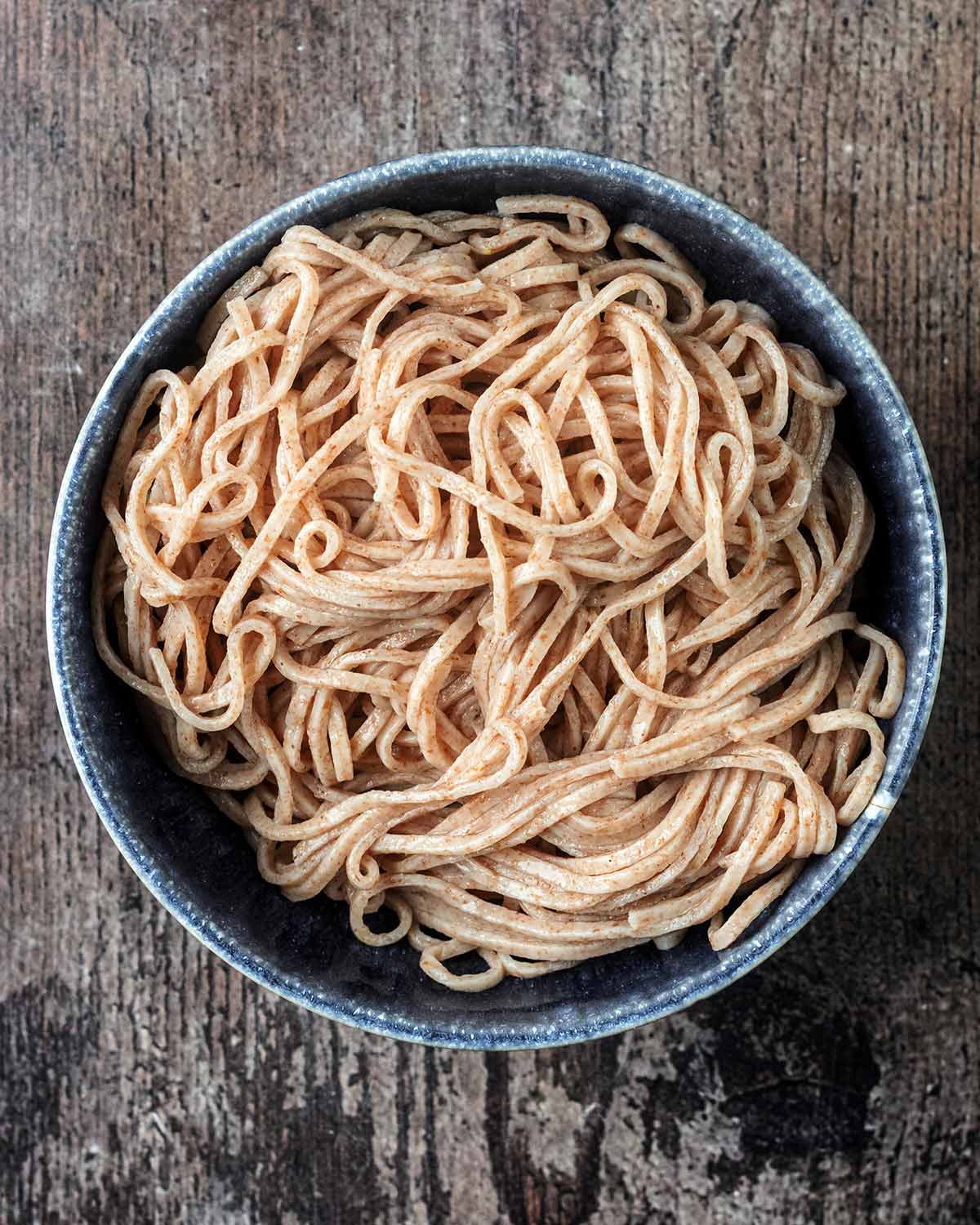 A bowl of cooked wholewheat noodles.