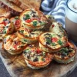 Ten cottage cheese egg bites piled up on a wooden board.