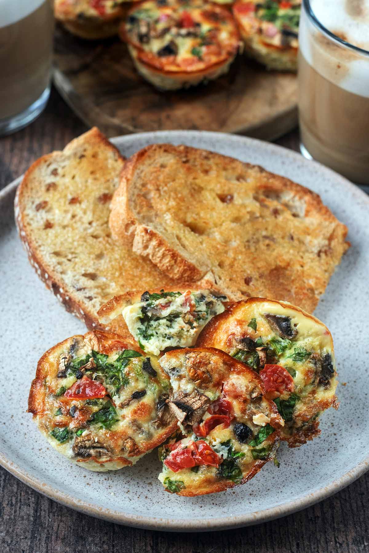 Three egg bites on a plate with some buttered sourdough toast.