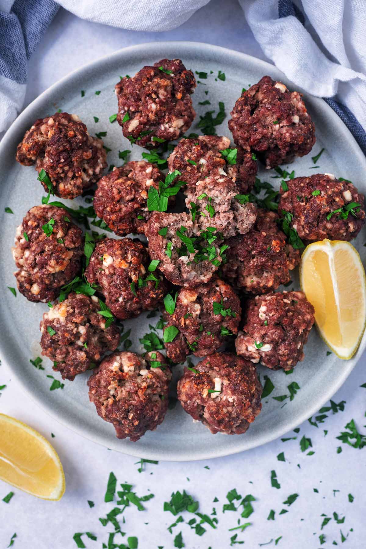 A plate of meatballs with chopped herbs scattered over them.
