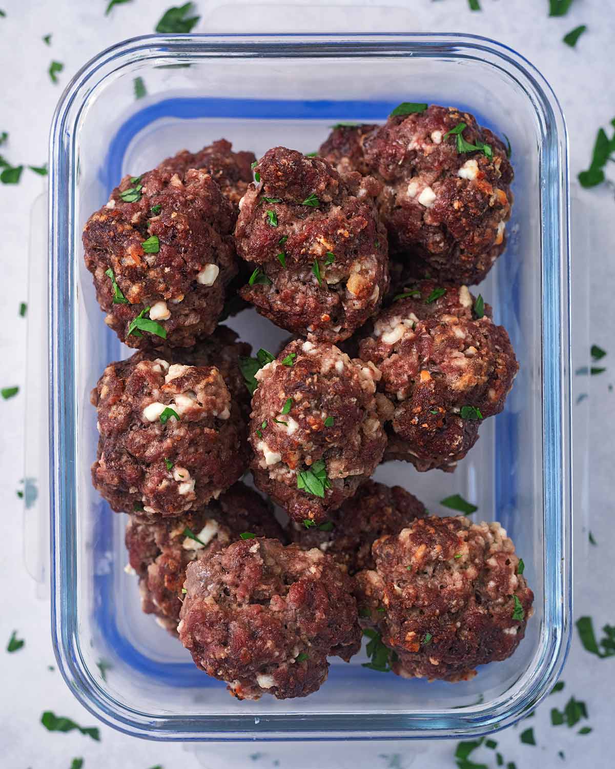 A glass container with cooked meatballs in it.