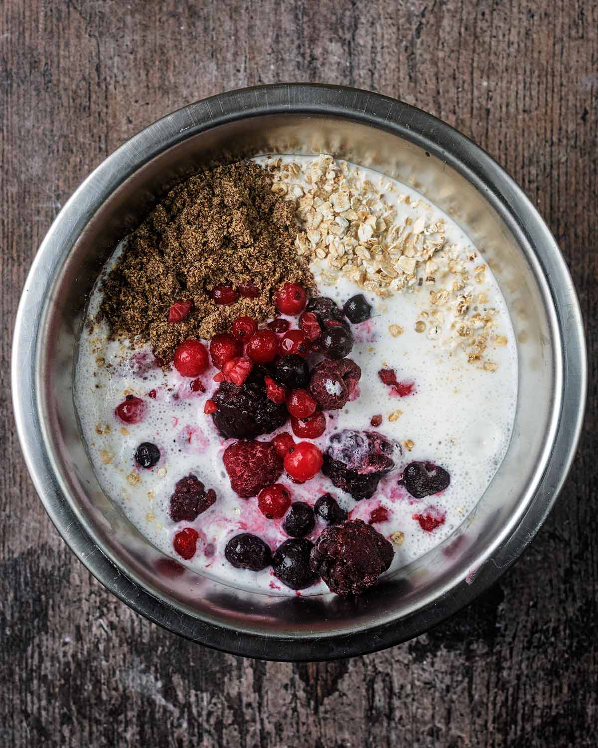 The cottage cheese and milk in a mixing bowl with berries, oats and flaxseeds.