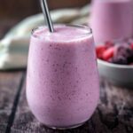 A pink cottage cheese smoothie in a glass with a straw.
