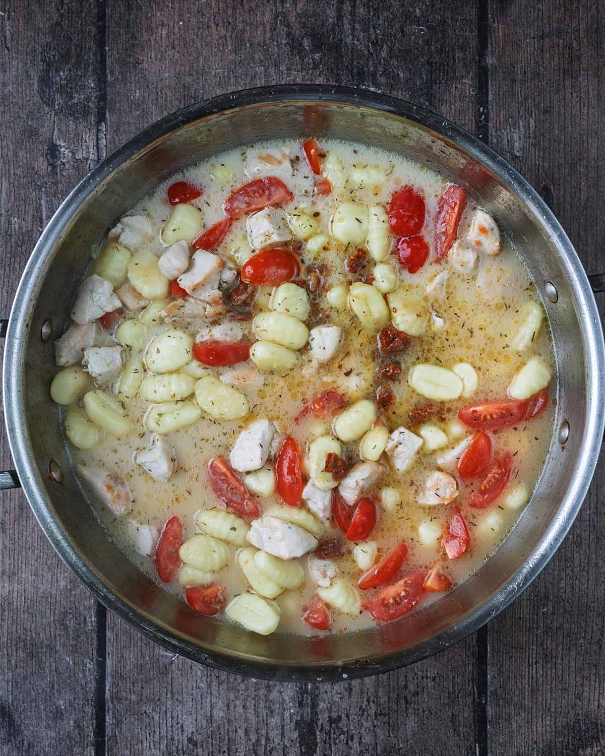 Stock and tomatoes added to the pan.